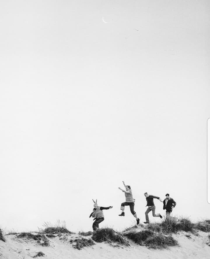 Friends jumping in the air on a sand dune